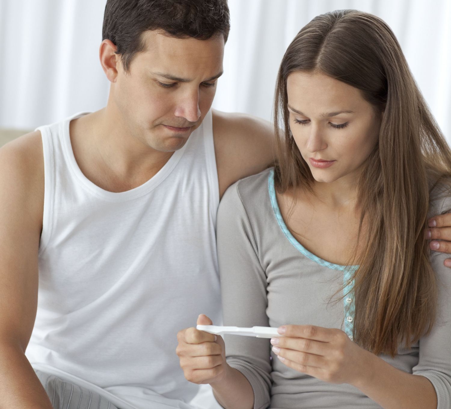 Eine Frau und ein Mann betrachten eine Schwangerschaftstest. Thema: Fruchtbarkeitsbehandlungen