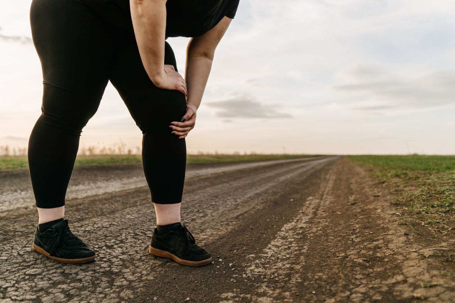 Frau hält beim Joggen an und stützt sich auf ihr Bein. Thema: Fettverteilungsstörung