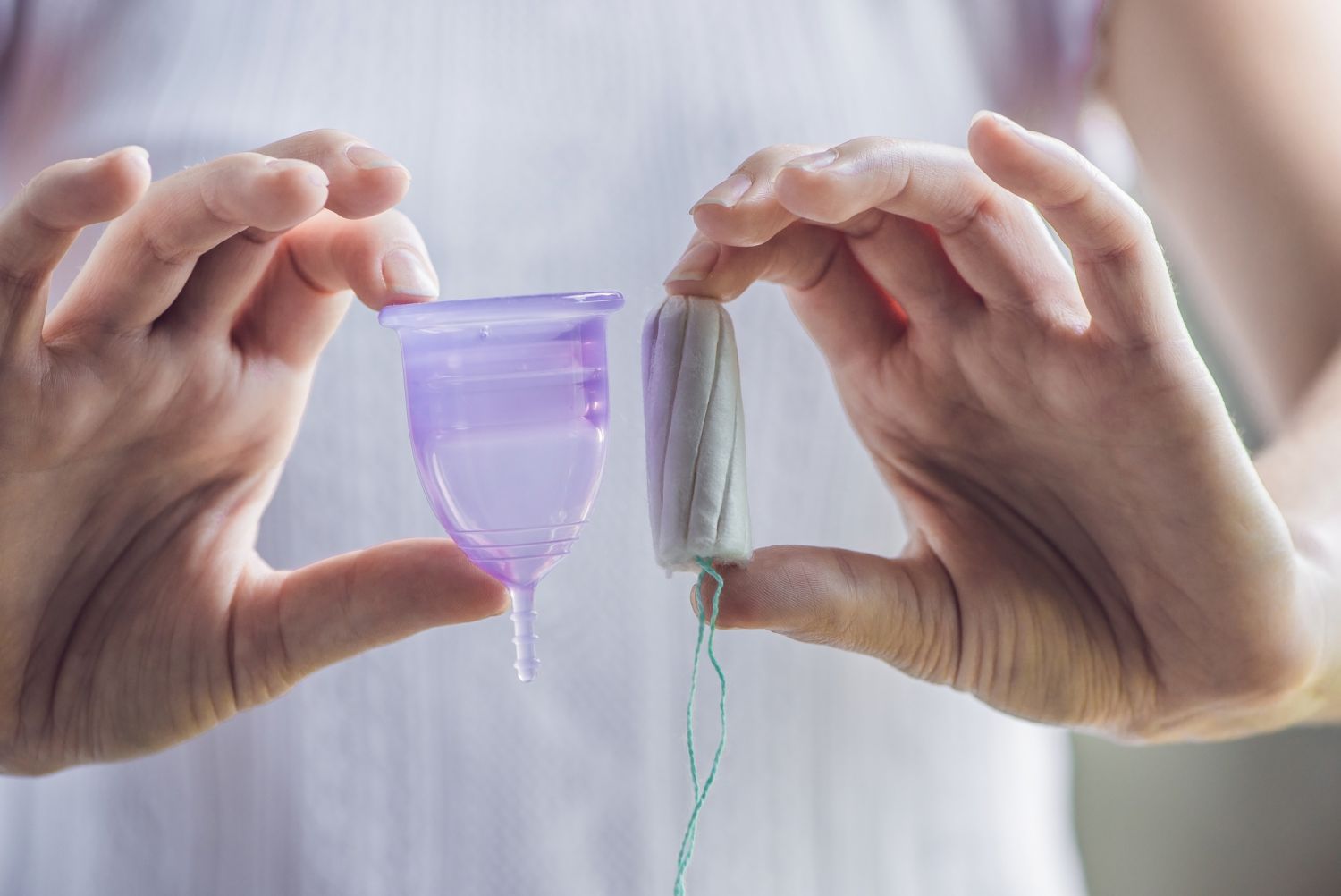 Eine Frau vergleicht einen Tampon mit einer Menstruationstasse