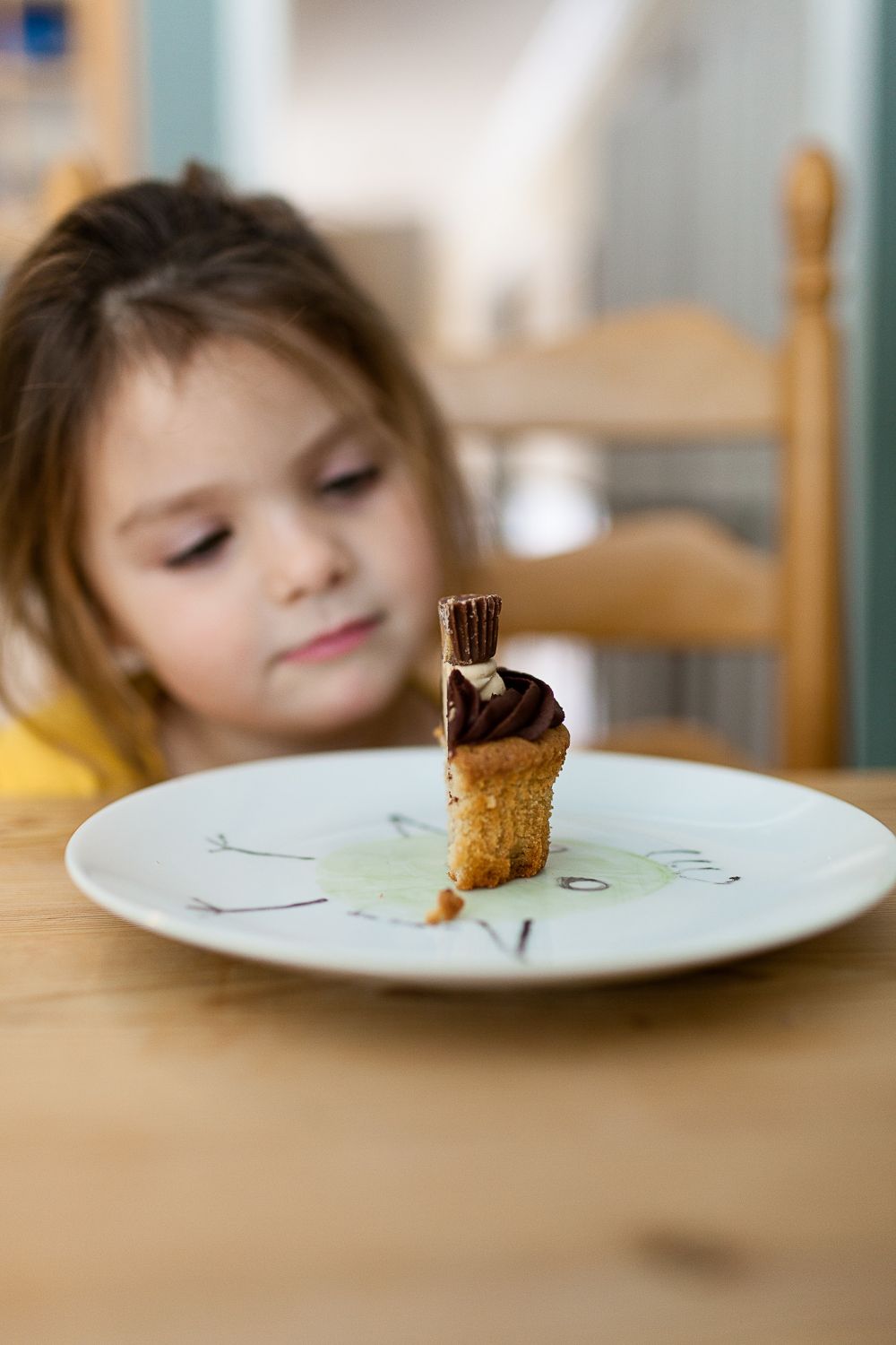  Ein Mädchen schaut auf einen Cupcake. Thema: Fragen zur Schwangerschaft