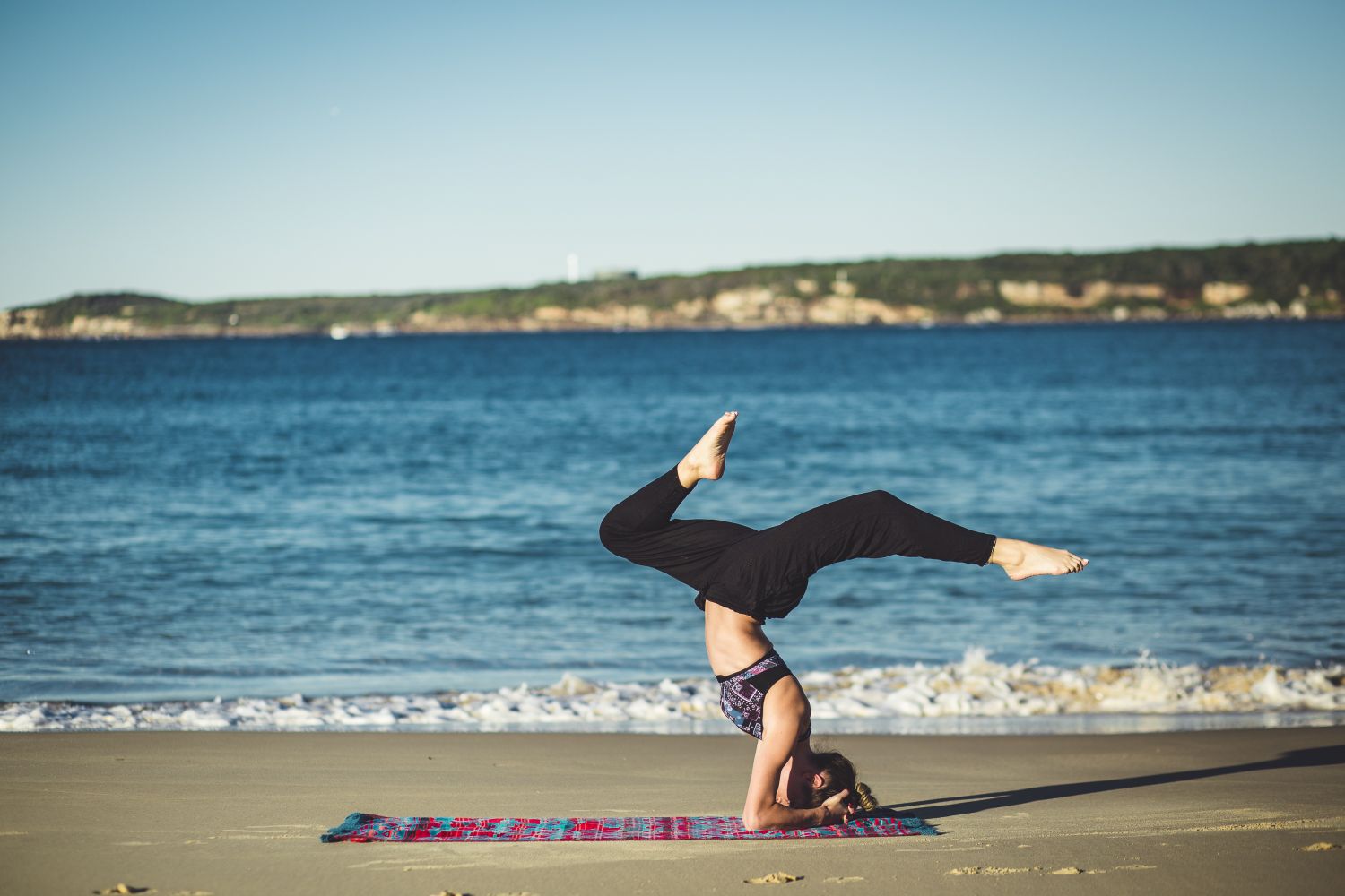 Eine Frau macht Yoga am Strand. Thema: Effekte von Yoga